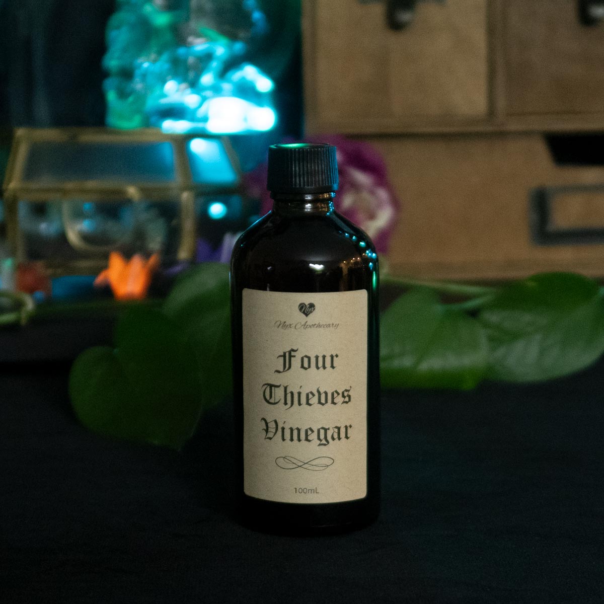 An amber glass bottle with a screw cap and antique-style label reading "Four Thieves Vinegar"