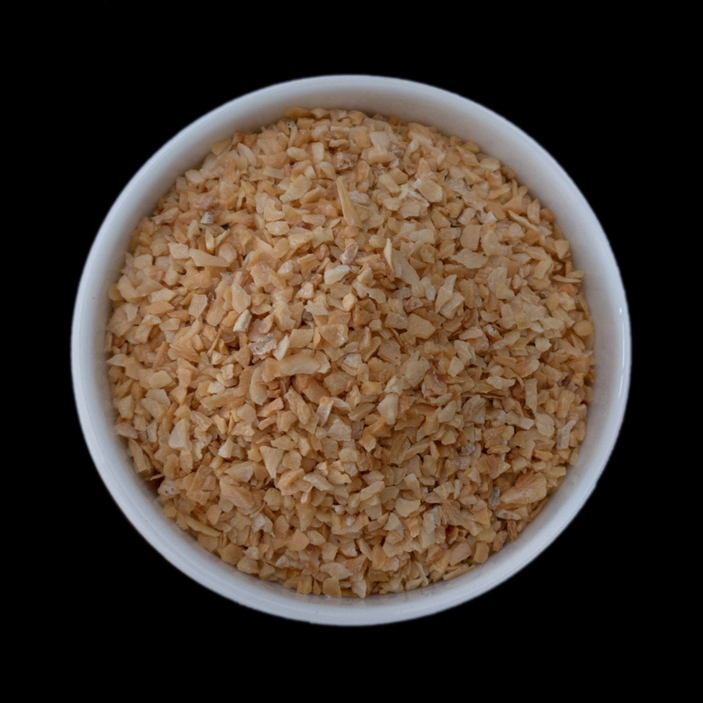 A small white bowl filled with garlic granules