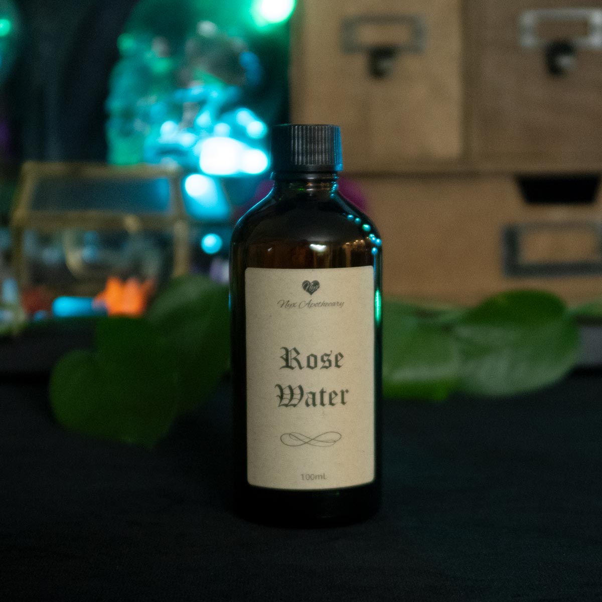 An amber glass bottle with a screw cap and antique-style label reading "Rose Water"