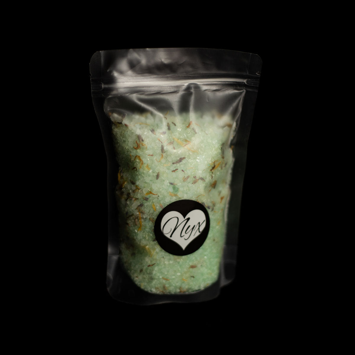 A clear/frosted bag filled with green bath salts with botanicals