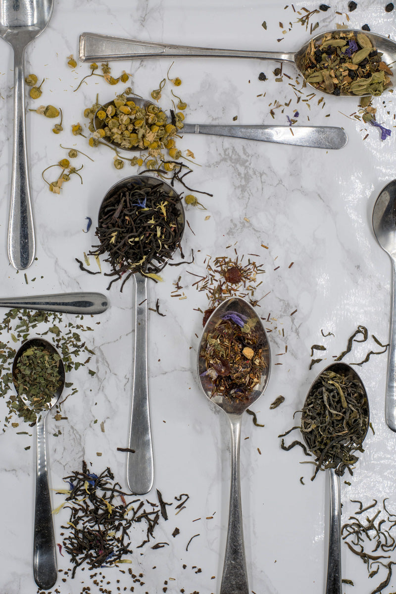 A collection of spoons holding a variety of herbs and teas