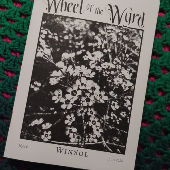 A hand flipping through a printed copy of the WinSol zine, in front of a crocheted background. 