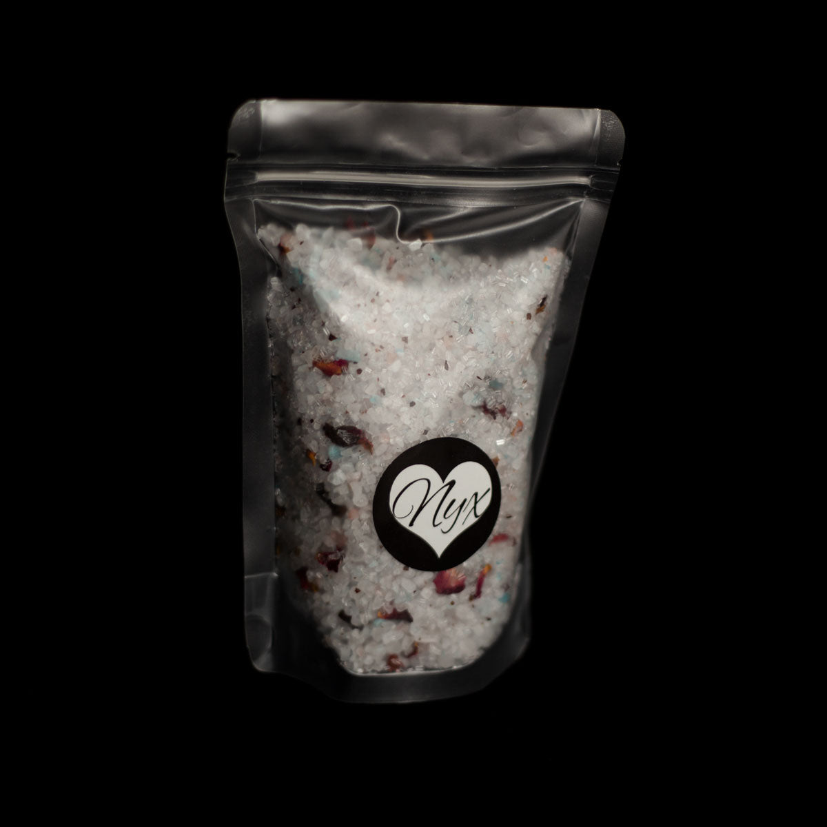 A clear/frosted bag filled with purple bath salts with botanicals