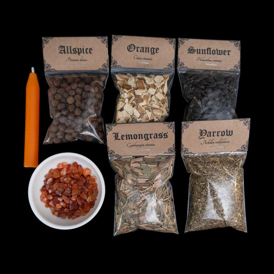 An orange chime candle, small bowl of carnelian crystal chips, and 5 bags of herbs with Victorian-apothecary-style brown labels at the top give the common and Latin names