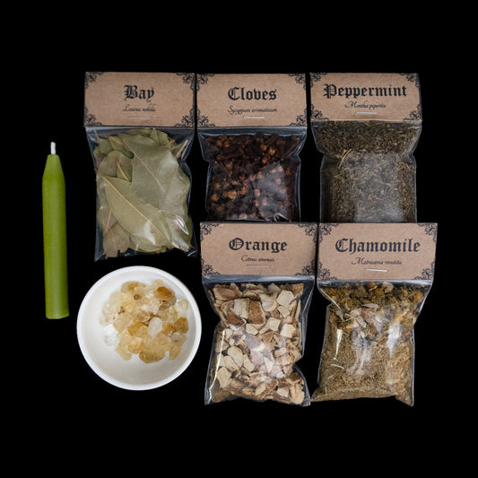 A lime green chime candle, small bowl of citrine crystal chips, and 5 bags of herbs with Victorian-apothecary-style brown labels at the top give the common and Latin names