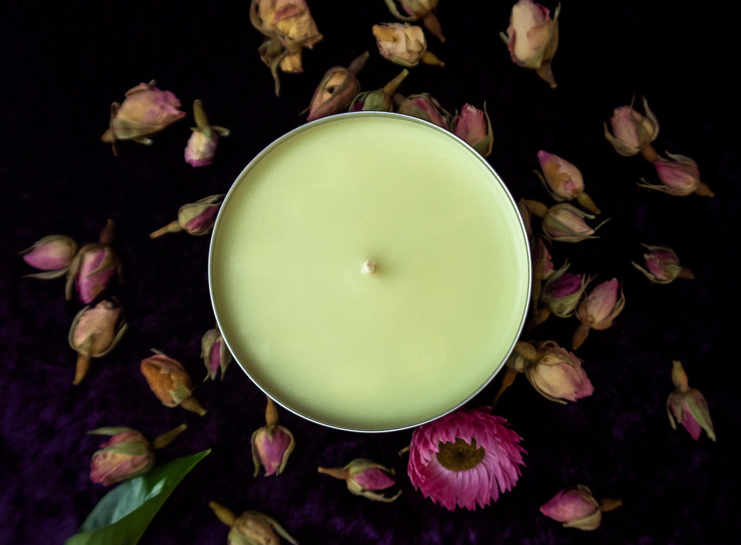 A pastel green candle in a black tin.