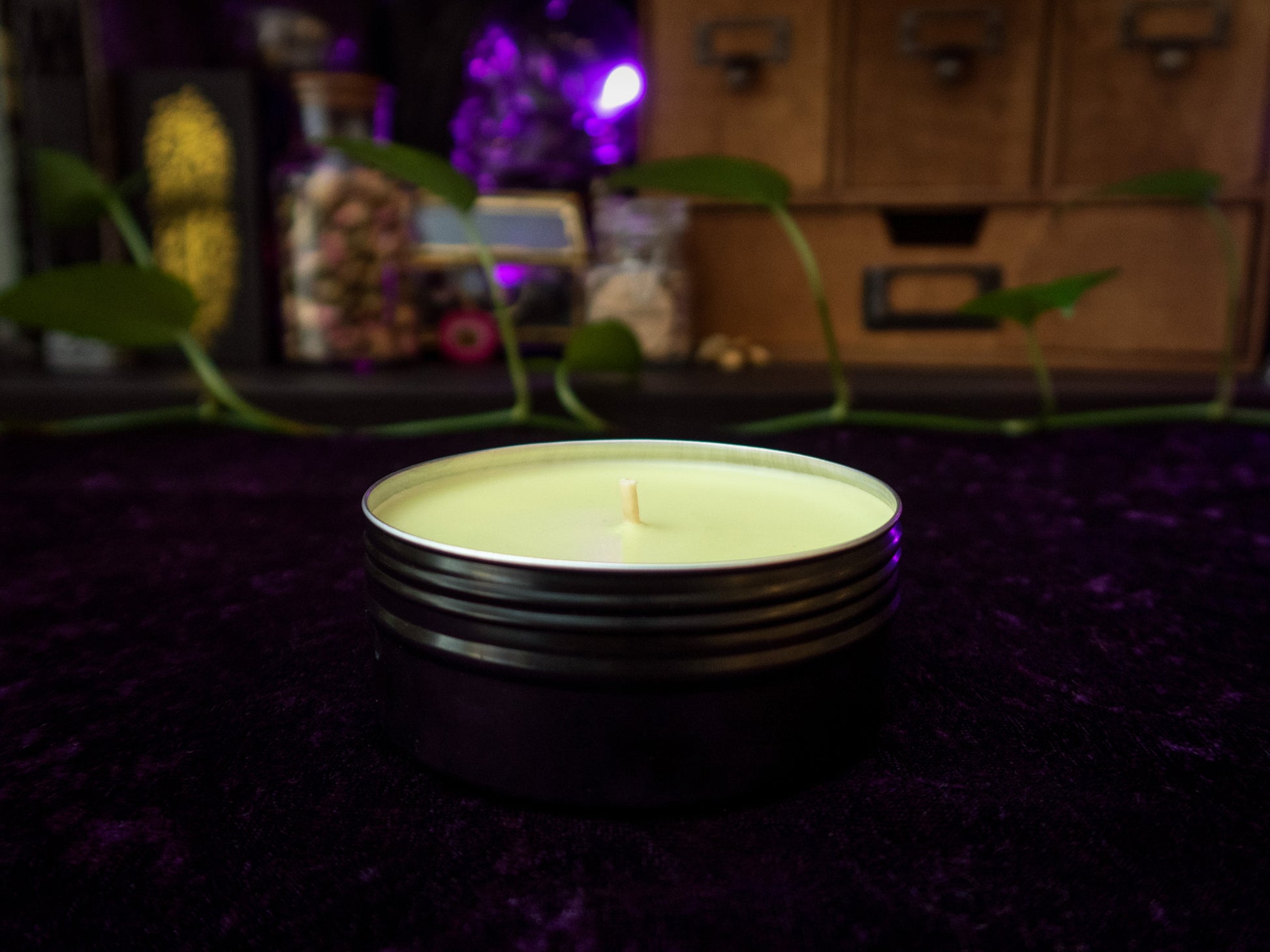 A pastel green candle in a black tin (side view).