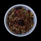 A small dish filled with an herbal tea blend, dominated by reds and yellows