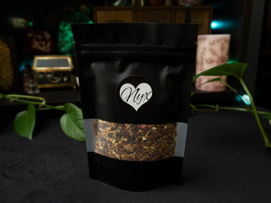 A black sachet with a window strip showing a bright herbal tea blend